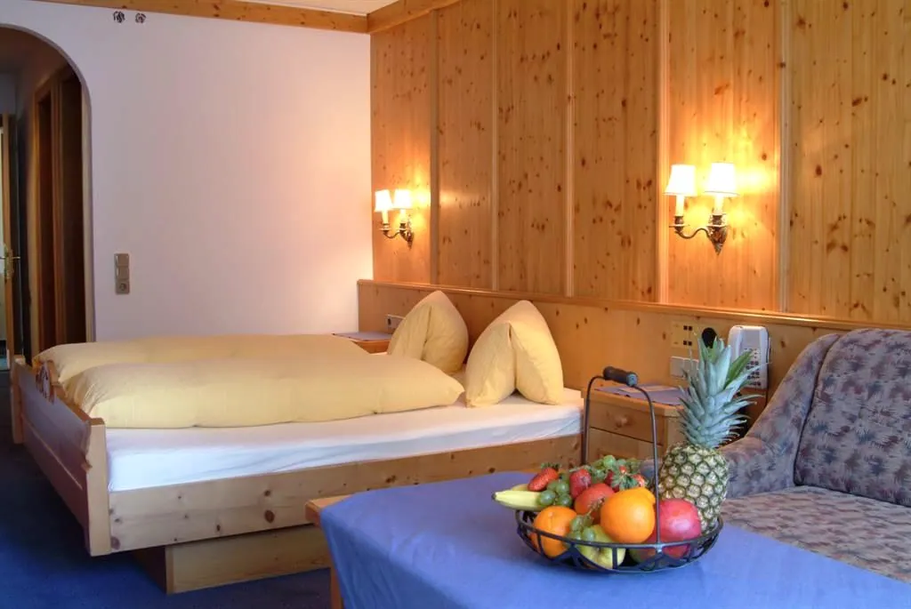 Familienzimmer mit Holzwand, Bett und einer Schale Obst